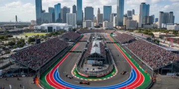 Formula 1 race car speeding on a track in a US city with a large crowd and urban landscape.